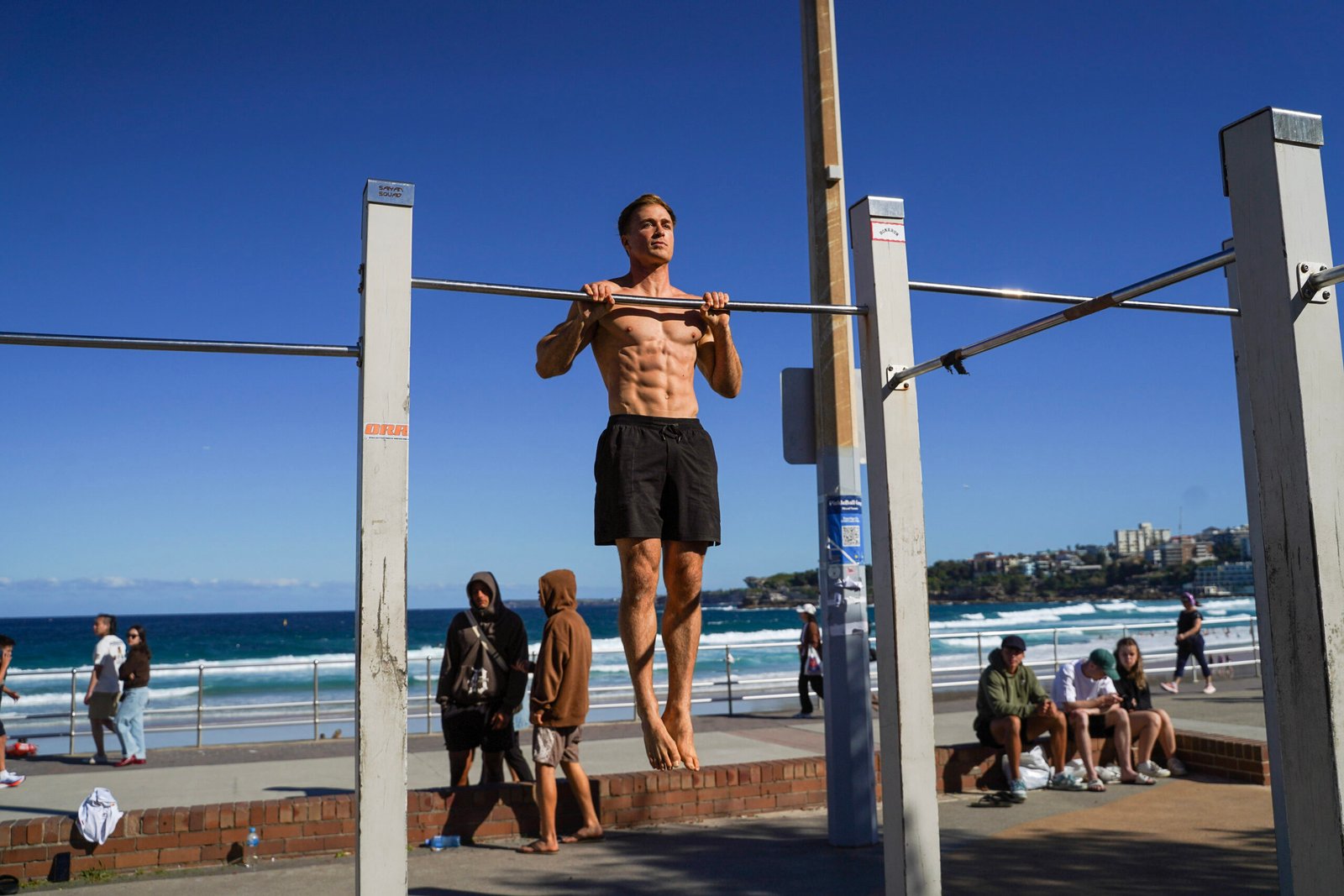 Jake Williams holding a pull-up at Bondi Beach
